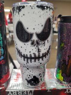 a couple of cups that have been decorated with skulls and flowers on them, sitting next to each other