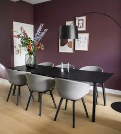 a dining room with purple walls and white chairs