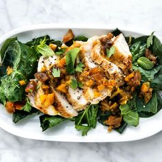 a white plate topped with chicken and greens