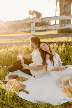 a man and woman sitting in the grass with food