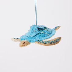 an ornament shaped like a sea turtle hanging from a string on a white background