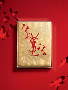 a red and gold square with the letter y on it is surrounded by paper butterflies