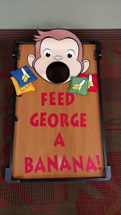 a cornhole board with a cartoon face and words feed george a banana on it