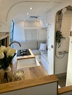 the interior of an rv with flowers in a vase on the kitchen counter and sink