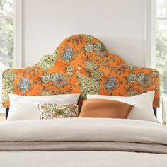 a bed with an orange headboard and pillows