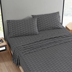 a bed with black and white bedspread next to a window in a room