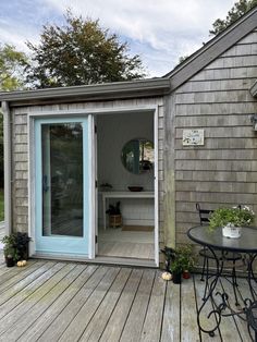 a small wooden deck with a table and chairs next to a door that leads into the back yard