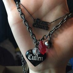 a person holding two different necklaces in their hand, one with charms and the other has a name on it