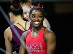 a woman smiling while standing next to other women in sports bras and vests