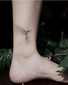 a small hummingbird tattoo on the right side of the foot, with leaves around it