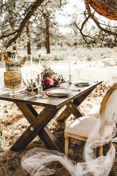 a table set for two under a tree in the woods