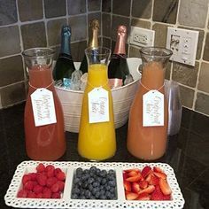 fruit, juice and champagne are on the counter in front of bottles with tags attached to them