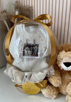 a teddy bear sitting next to a gift bag with a baby's photo on it