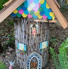 a fairy house made out of a tree stump with balloons on the roof and windows