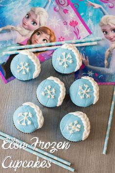 frozen cupcakes with blue frosting and snowflakes are on the table