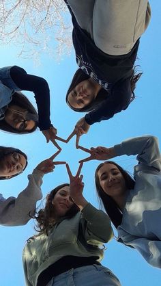 four girls are standing in a circle and making a star with their hands while looking up at the sky