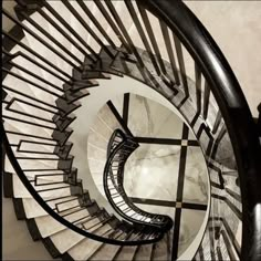 a spiral staircase with marble floors and black railings