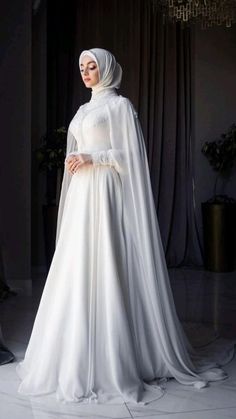 a woman in a white dress and veil is posing for the camera with her hands on her hips