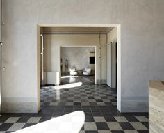 an empty room with black and white checkered flooring on one side and light coming in from the other