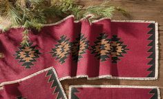 three red rugs with black and brown designs on them next to a pine tree