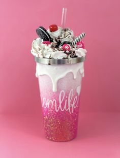 a pink and white cup filled with whipped cream, candy canes and candies