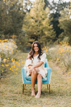 a woman sitting on a blue chair in the grass