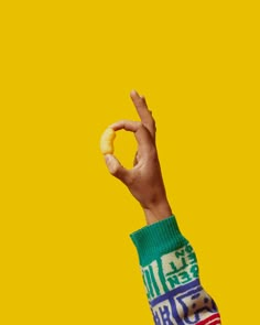 a person's hand holding up a doughnut in the air with their fingers