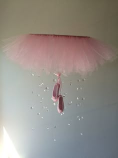 a pink tutule and ballet shoes hanging from the ceiling