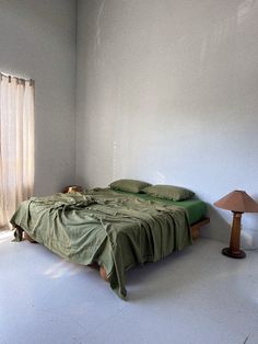 a bed sitting in the middle of a room next to a lamp and window with curtains