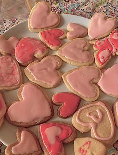 some heart shaped cookies on a plate with pink icing and hearts in the middle