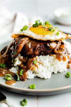 a plate topped with rice and meat covered in gravy