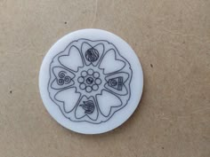 a white plate with black designs on it sitting on a brown table next to a wall