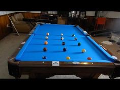 a blue pool table with several balls on it in a room filled with other items