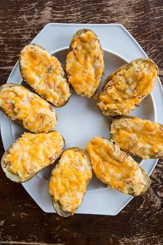 a white plate topped with cheese covered muffins on top of a wooden table