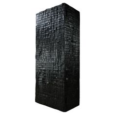 a tall black brick sculpture on a white background