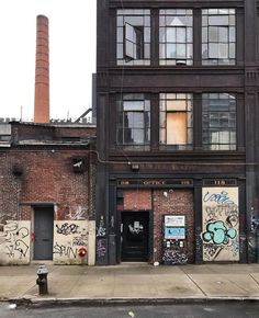 an old brick building with graffiti on it's walls and windows in front of a fire hydrant