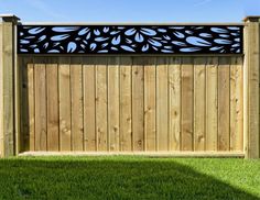 a wooden fence with an intricate design on it's top and bottom panel, in the grass