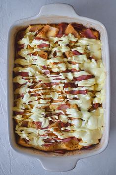 a casserole dish with potatoes, bacon and cheese in it on a white surface