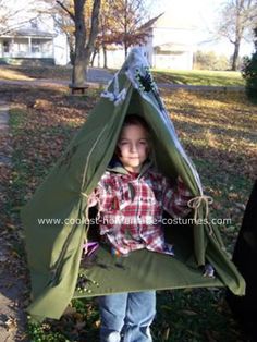 a young boy is standing outside in a teepee