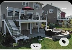 an outdoor patio with seating and umbrella in front of two story house on grassy area