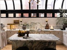 a large kitchen with marble counter tops and black framed windows, along with white cabinets