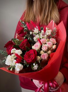 a woman is holding a bouquet of roses in her hands and wearing a red hoodie