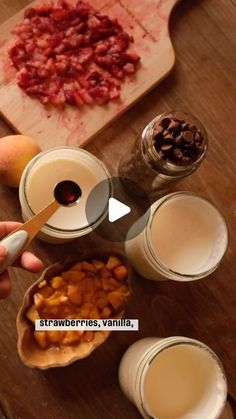 a person is holding a spoon over some fruit and milks on a wooden table