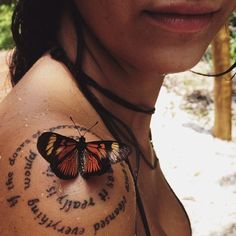 a woman with a butterfly tattoo on her arm and chest is looking at the camera