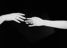 two hands reaching out towards each other in black and white, against a dark background