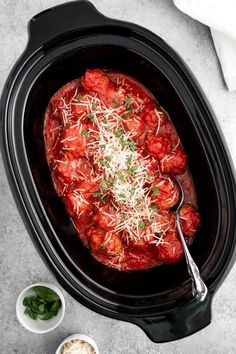 a slow cooker filled with meat covered in marinara sauce and parmesan cheese