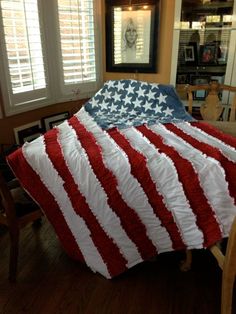 an american flag quilt on top of a bed in a room with wooden floors and windows