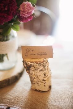 a vase filled with flowers sitting on top of a table next to a wooden slice