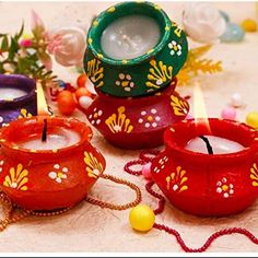 three colorful candles sitting on top of a table next to flowers and beads in vases