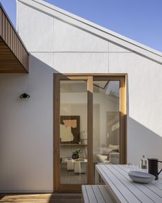 a white house with wooden decking and sliding glass doors that open up to the outside